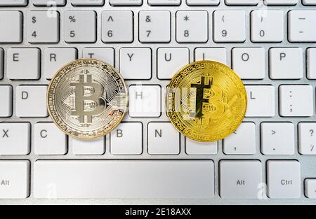 Bitcoins silver and gold color on keyboard. New Virtual money concept. Golden coin with icon letter B or blockchain technology Stock Photo