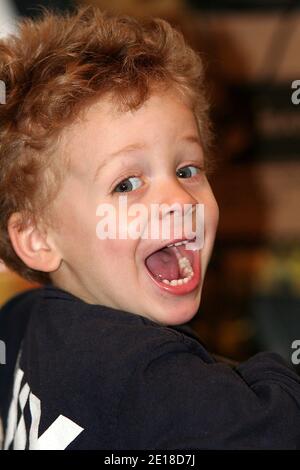 New York, NY, USA. 11 January, 2006. Young boy indoors looking over the shoulder making a funny smiley face - S.D. Mack Stock Photo Collection at Broo Stock Photo