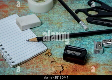 Small notebook, black pencil, eraser and other stationery on a rustic surface. Work items concept. Stock Photo