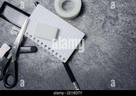 Small notebook, black pencil, eraser and other stationery on a rustic surface. Work items concept. Stock Photo