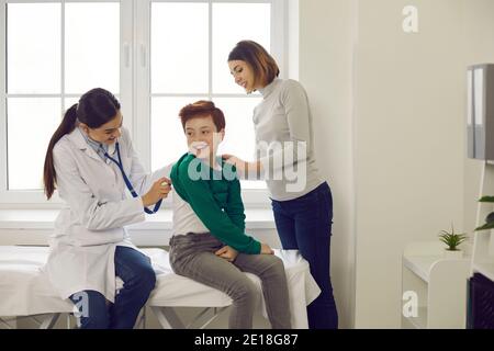 Family doctor listening to breath of little patient during check-up at the clinic Stock Photo