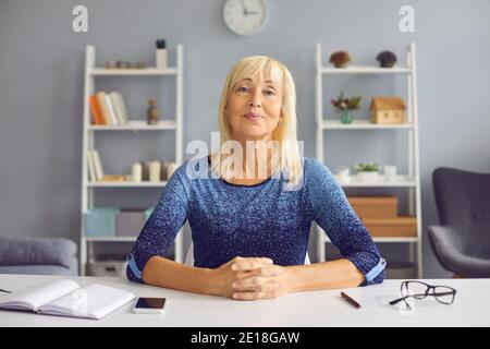 Mature woman remote teacher in the distance providing virtual counseling while sitting at home. Stock Photo