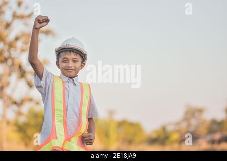 Boy white helmet hard hat safety showing hand up success,Engineering dream of future Stock Photo