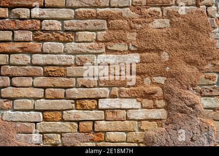 Background from a red rough brick wall with the remains of some plaster Stock Photo