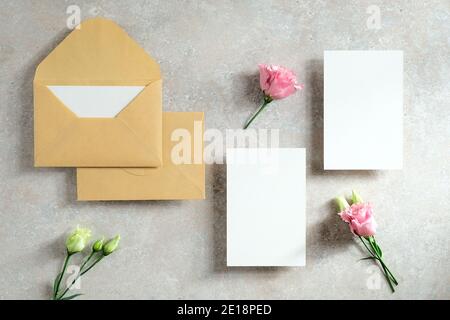 Wedding invitation cards design. Flat lay, top view blank paper cards, envelopes, flowers on stone background. Stock Photo