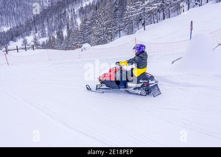 A men in protective sportswear riding snowmobile Branas Ski Resort