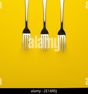 three forks arranged on a yellow surface Stock Photo