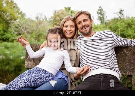 Portrait of happy family sitting on bench Stock Photo