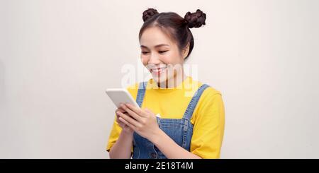 Excited beautiful woman receiving SMS in mobile phone over plain background Stock Photo