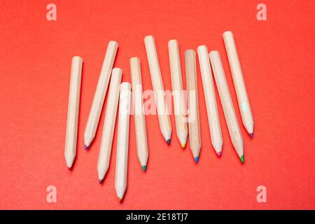 Colored pencils on red background. Many different colored pencils. Stock Photo