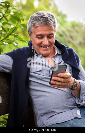 Smiling senior man using phone Stock Photo