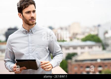 Young man standing outdoors with digital tablet Stock Photo
