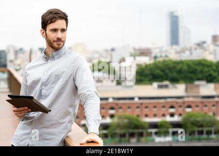 Young man standing outdoors with digital tablet Stock Photo