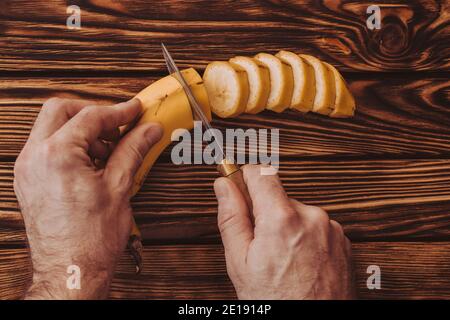 Man cuts banana into rings on board - serving fruit Stock Photo