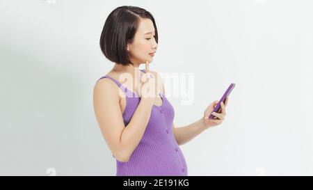 Young Asian pregnant woman using mobile phone over white Stock Photo