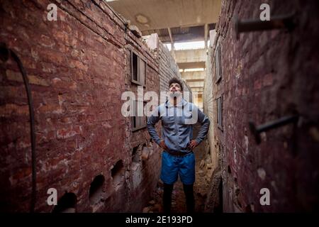 Portrait of focused motivated afro-american young handsome sportive man with earphones standing inside of the abandoned place in the middle of two wal Stock Photo