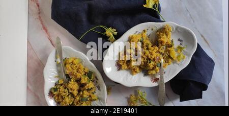 Two oval plates of yellow quinoa with courgettes and peaches Stock Photo