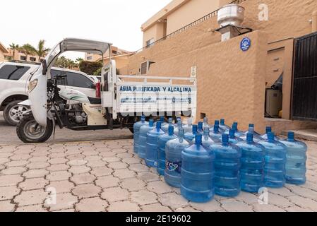 A large group of purified water bottles on the ground by a delivery truck. Stock Photo