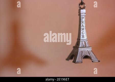 Metal keychain in the form of the Eiffel Tower in Paris, France. Souvenir from the trip close-up on orange background Stock Photo