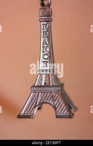 Metal keychain in the form of the Eiffel Tower in Paris, France. Souvenir from the trip close-up on orange background Stock Photo