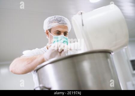 Man in factory making gel for face creams by combining diferente engridiens. Stock Photo
