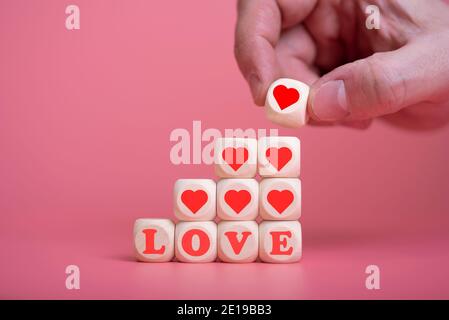 love valentine's day conceptman hand holding the heart to put on the cube wooden to mean the love on valentines day. The concept of love and happiness Stock Photo