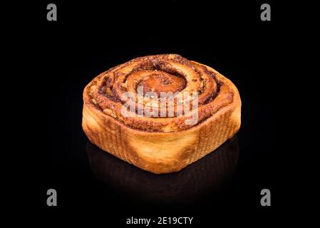 Freshly baked sweet bun with raisins and cinnamon isolated on black background. Homemade traditional bakery, baking bread and sweets concept Stock Photo