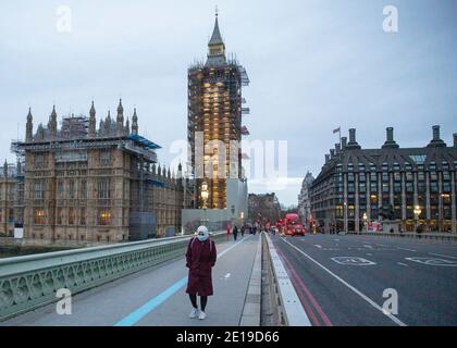 A masked woman walks across a quiet Westminster Bridge, Central London on the morning of the 5th of January 2021 as the National lockdown takes effect Stock Photo