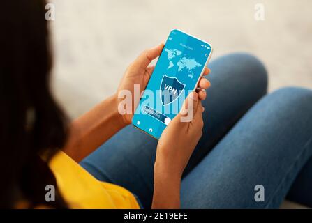 Black woman holding and using cellphone with vpn app Stock Photo