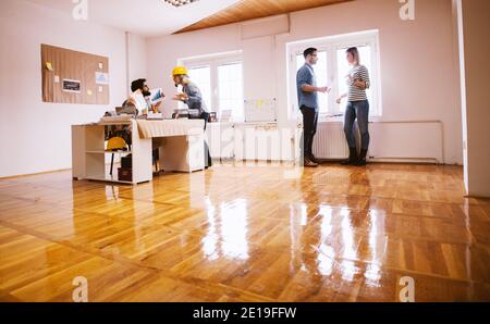 Four young engineers talking in the office. Two of them argue at the desk about analyse of a project. Stock Photo