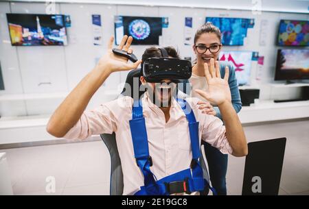 Gorgeous youthful hipster couple having fun while checking out VR in the tech store. Stock Photo