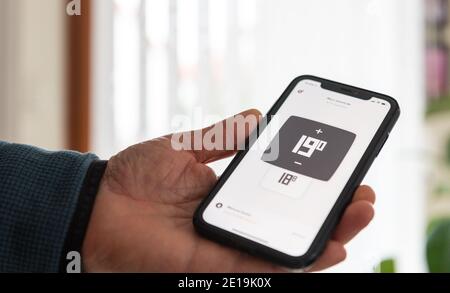 Man controlling the heating of his house with an application on his telephone Stock Photo