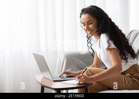Young lady attending webinar, using laptop and headset Stock Photo