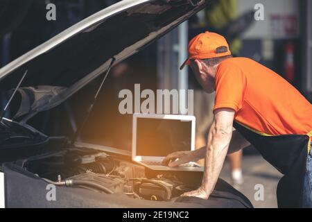 Car maintenance service, technician diagnose car engine failure problem by laptop computer. Stock Photo