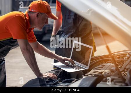 Car maintenance service, technician diagnose car engine failure problem by laptop computer. Stock Photo