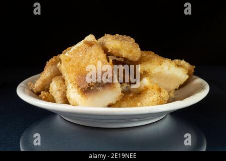 The Bit of roasted fish in white plate on table with reflection. Products of the feeding on black background Stock Photo