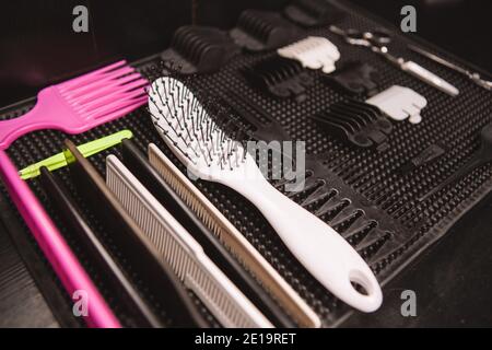CLose up of various hair brushes and combs on the desk of a professional barber at the barbershop. Hair care, profession, tools concept Stock Photo