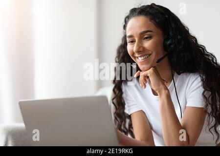 Closeup of happy young woman with headset using laptop Stock Photo