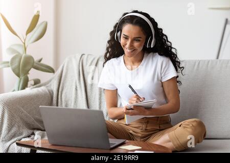 Cheerful lady attending webinar, using laptop and wireless headset Stock Photo