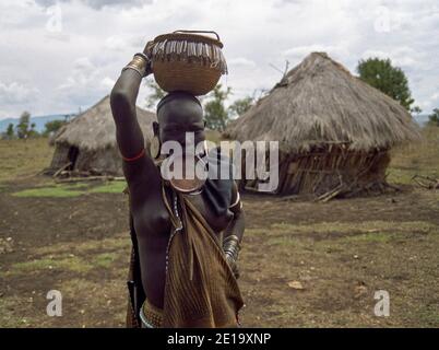 Mursi tribe woman with lip plate and basket on her head, Omo Valley, Southwestern Ethiopia Stock Photo