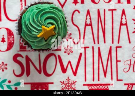 Christmas tree with gold star cupcake cup cake from box of M&S 9 mini festive cupcakes set on Christmas serviette napkin Xmas Stock Photo