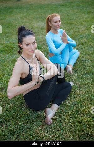 Vertical shot of two young healthy fit women doing yoga outdoors Stock Photo