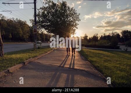 Silhouette of two people on the street at sunset. The beautiful sunset in the city. Stock Photo