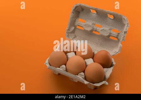 Egg box with eggs, six chicken eggs in cardboard egg tray made from recycled paper isolated on orange  background Stock Photo