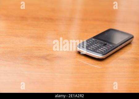 Obsolete dusty push-button phone on the table. Close-up. Stock Photo