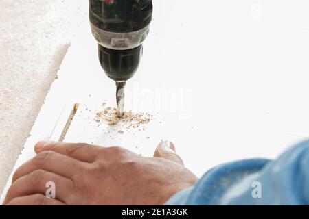 worker drills a hole when assembling furniture. Stock Photo