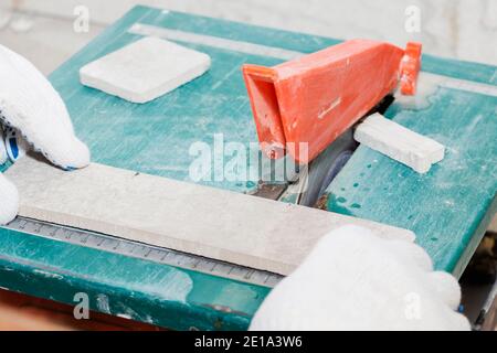master cuts the tiles on the saw. repair of apartments and houses Stock Photo