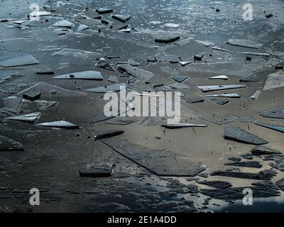 Broken ice on puddle, England in winter. Abstract pattern. Stock Photo