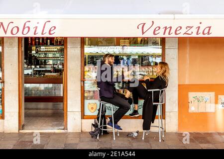 A Happy Couple Drinking Coffee and Eating Pastries Outside A Cafe In Venice, Italy. Stock Photo