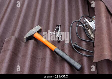 Close up view on asphalt roofing shingles background with hammer and nails Stock Photo